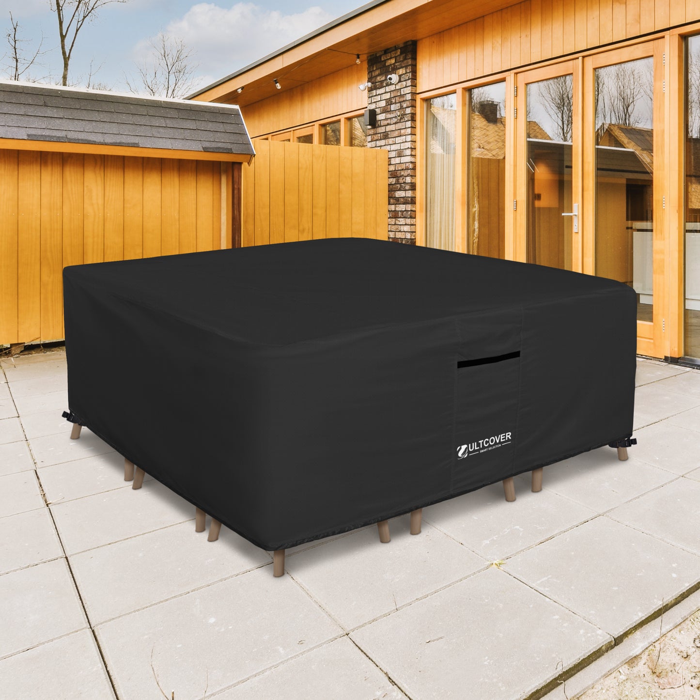 Black outdoor furniture cover on a patio with wooden cabin in the background black